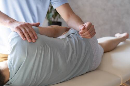 Close up physiotherapist helping patient with pain